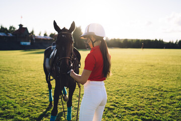 Female jockey with horse on meadow