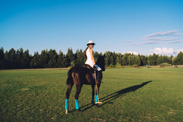 Female Polo player riding horse on green field
