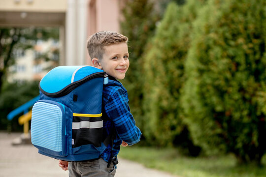 Little first grader with a blue backpack goes to school