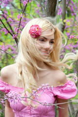 Obraz na płótnie Canvas Pretty happy blonde fluffy hairs woman posing in spring blooming park