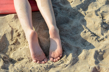 Women's feet on the sand by the sea. summer rest