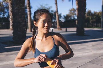 Thoughtful female in activewear holding sport water bottle for refreshing on break after jogging on...