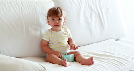 One year old baby toddler boy sitting on sofa coughing, sweet adorable infant child