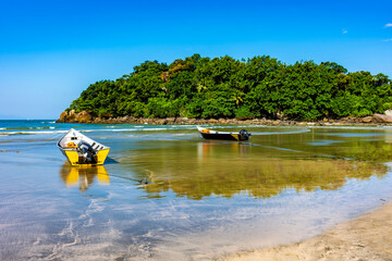 Stunning Withe beach in bertioga in state of Sao Paulo with rainforest, the sea and speedboats anchored in the sand