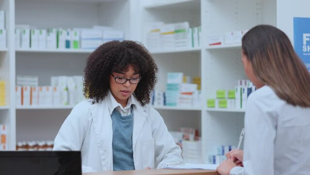 Pharmacist talking, helping and giving customer medicine in pharmacy after explaining prescription. Medical healthcare professional with afro selling drugstore medication pill after signing paperwork