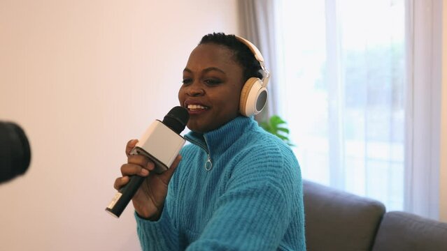 African american woman recording music tutorial with camera at home looking positive and happy standing and smiling singing social media influencer