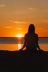Fototapeta premium soft selective focus, yoga meditation, silhouette of woman at sunset in lotus position. health recreation and sports, outdoor training. poster.person is engaged in breathing practices. mental health