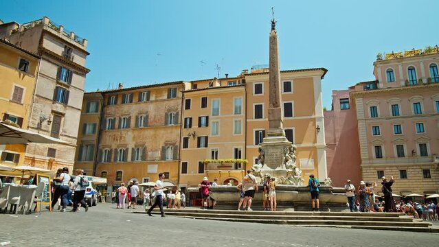 Tourists visit the Elegant square with baroque fountains and street artists. The famous Statue of the God Zeus in Bernini's Fountain of the Four Rivers in the Piazza Navo