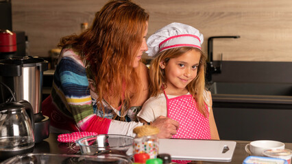 Mother and daughter dressed as a cook in the kitchen