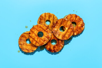 Grilled pineapple with rum sauce, minimalist on a blue background.