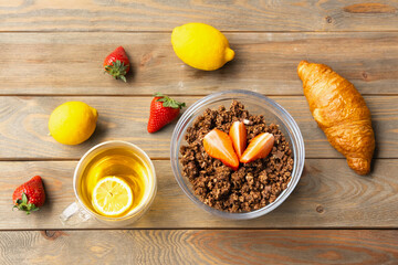 Gourmet Muesli with chocolate and fruit tea with lemon on wooden background. Healthy breakfast with french croissant. Close-up