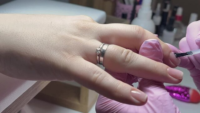 Manicure service of our own manufacture. Applying nude nail polish. manicure process. Application of nail polish on nails.
