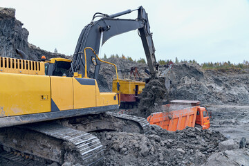 modern excavator loading soil into truck at construction site - 587075580