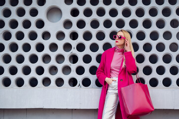 Fashionable confident woman wearing fuchsia color coat, sunglasses, pink turtleneck, metallic...