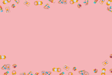 Many cute wooden rattles for baby on pink background. Eco-friendly toys for newborns in the colors of the rainbow. Flat lay, copy space.