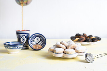 Obraz na płótnie Canvas Traditional arabian cookies (kahk) sprinkled with white sugar and a cup of tea and petit four cookies 