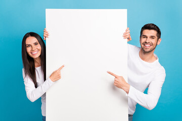 Photo of two positive nice people indicate finger empty space proposition isolated on blue color background