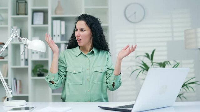 Stressed businesswoman worker entrepreneur working on laptop computer covering ears with hand annoyed by noisy neighbours colleagues suffers wishes silence at workplace Office without sound insulation