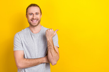 Photo of confident positive man wear grey t-shirt showing thumb emtpy space isolated yellow color...