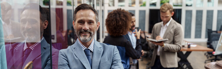 Obraz premium Portrait of mature businessman standing in modern office on colleagues background