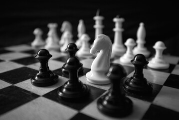 a white chess horse is surrounded by black pawns on the board