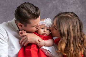 Young dad and mom tenderly kiss their little girl. Love and tenderness of parents. Portrait. Close-up