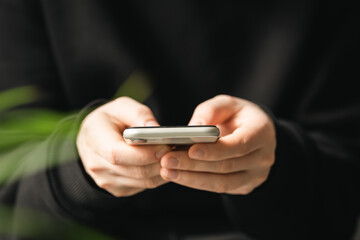 Smartphone in the hands of a man close-up on a blurred background, the concept of using technology, shopping online, communicating remotely.