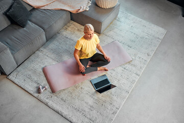  Top view. Beautiful adult woman doing exercise at home on mat in living room. Sports, leisure, home interior.
