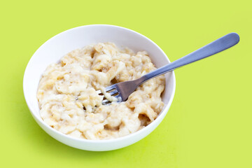 Mashed bananas in bowl on green background.