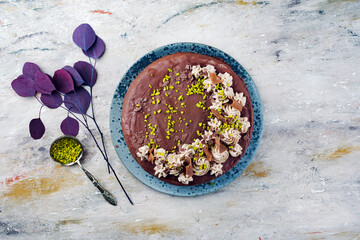 Traditionelle Nougat-Torte mit Schokoladenglasur, Sahnehäubchen und gehackten Pistazien serviert...