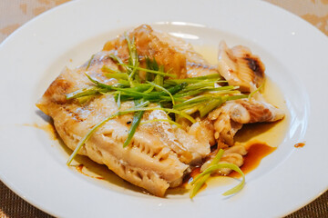 Steamed fish in black bean sauce arranged in a white plate