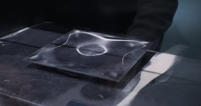 An experiment with the movement of sand under the influence of sound vibration White sand moves on the surface depending on the strength of the sound wave. Scientific experiment with sand vibration.