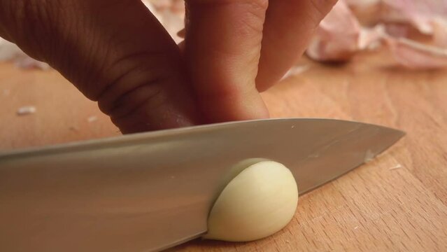 The knife cuts the garlic clove lengthwise