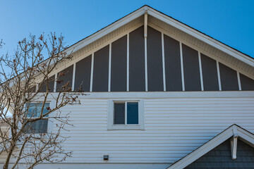 Top of a house with nice windows in the blue sky background. Beautiful Home Exterior. Real Estate Exterior Front House