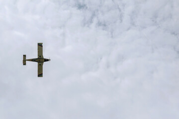 A small first-class plane flies in the cloudy sky. View from below. Horizontal orientation.