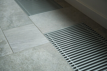 Fototapeta premium Heating grill with ventilation in the floor in laminate.. Forced hot-air heating systems are extremely popular and feature vents like this to channel the hot air throughout the house.