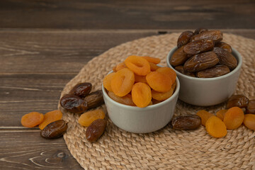 Dried apricots and dates fruits on dark wood background with copy space.
