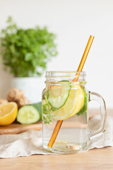 Infused  water with cucumber, lemon and ginger in glass bottle on wooden table. Diet, detox, healthy eating, weight loss concept