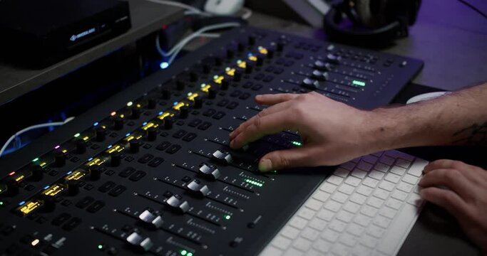 A sound producer hand is using a music mixer with editing tools in recording studio