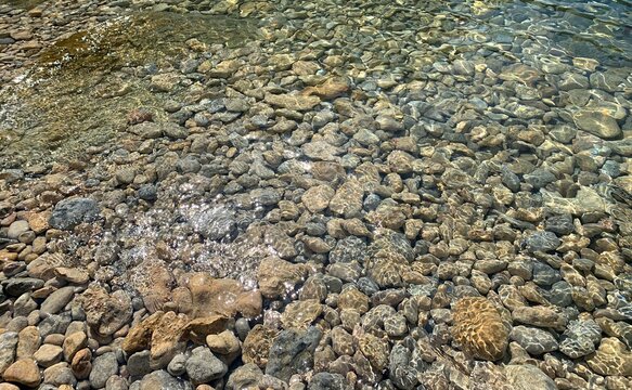 Pebbles stones on the beach in clear sea water.