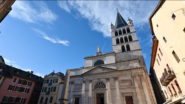 Annecy, France. January 2023. Tilt footage with the facade of the church of notre dame in evidence. Beautiful sunny day with blue sky and white clouds. People in the square.