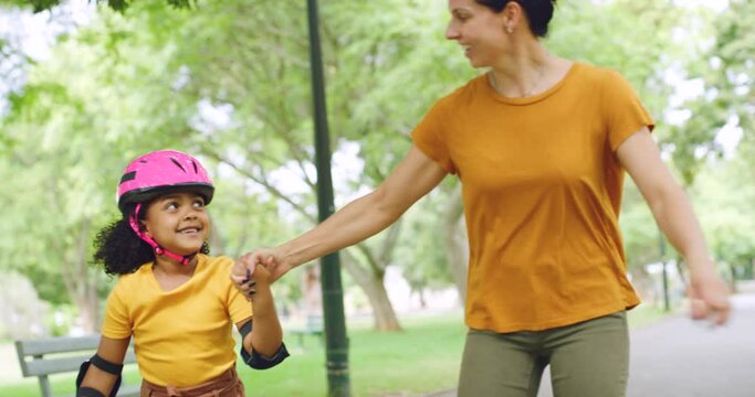 Single mother skating with adopted mixed race daughter in park. Young single parent enjoying free time with adorable girl rollerskating outside. Happy cute child bonding with woman