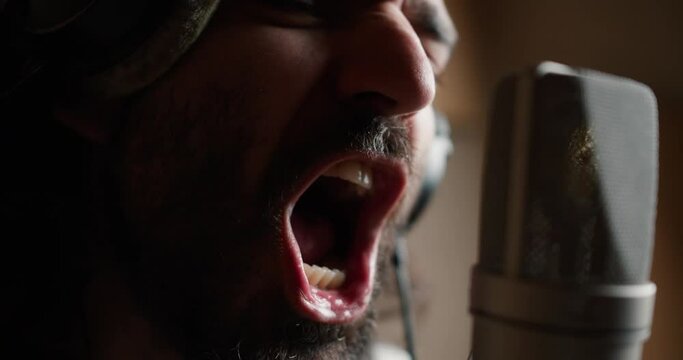Close up of a bearded man performing new song, singing into microphone with passion and drools are coming out