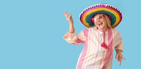 Dancing mature Mexican woman in sombrero hat on light blue background with space for text