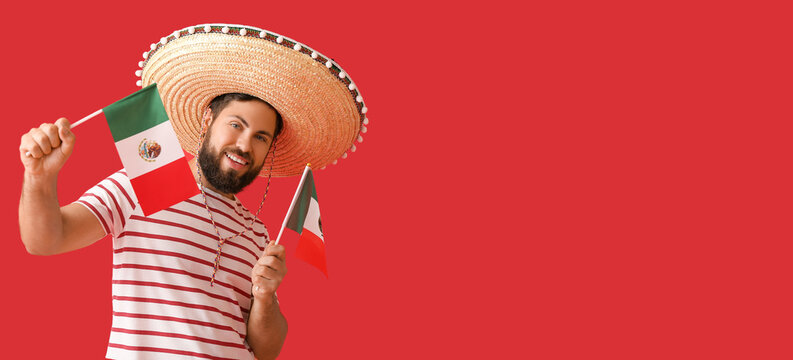 Handsome man in Sombrero and with Mexican flags on red background with space for text