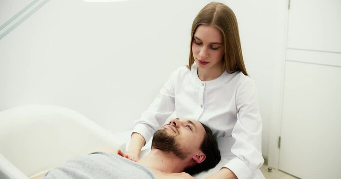 Female master doing therapeutic massage of the head and neck for man