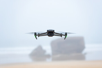 Drone flying on a beach at low altitude. Front view of the drone and its camera. Out of focus background. Latest technology on the market