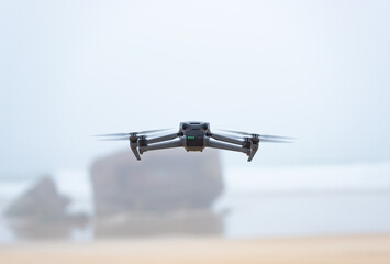 Drone flying on a beach at low altitude. Rear view of the drone. Out of focus background. Latest technology on the market