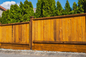 Nice new wooden fence around the house. Wooden fence. Street photo, Real Estate Exterior Front House on a sunny day