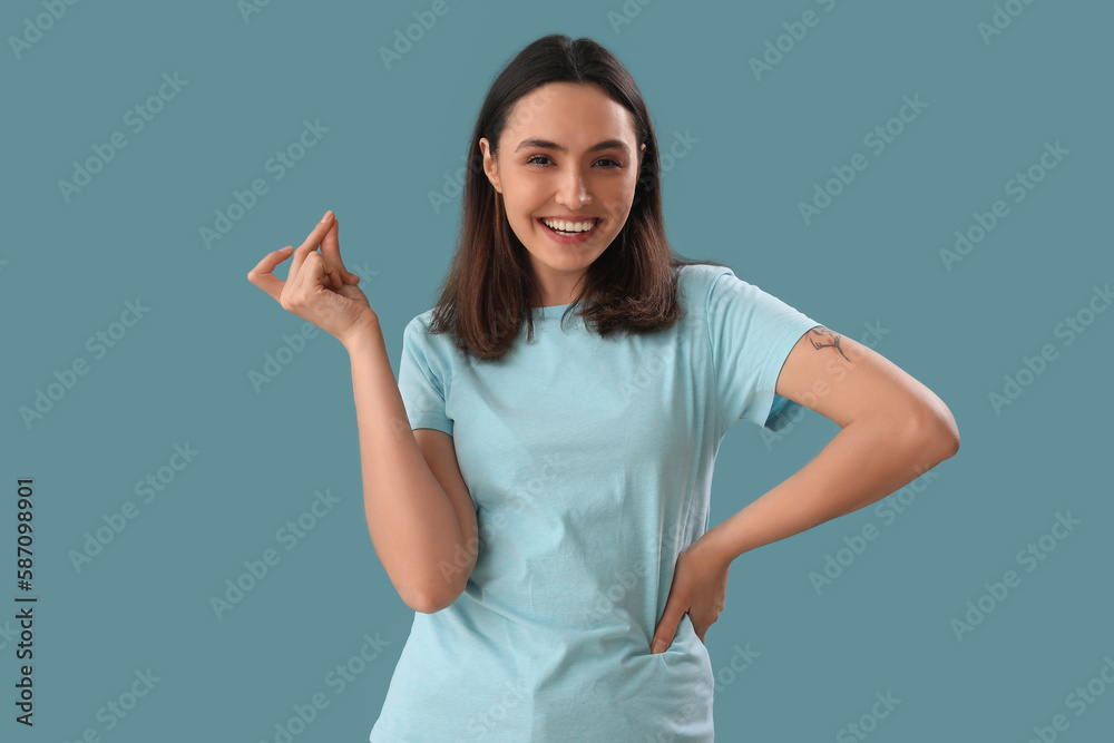 Wall mural young woman snapping fingers on blue background